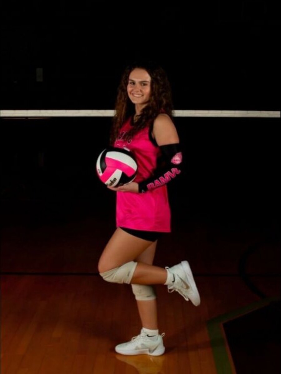 Josey Moore holding a volleyball in a gym